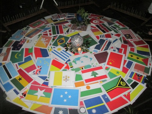 Mandala realizado con banderas de los distintos países, un centro esférico y una  vela encendida. Mandala made with flags of different countries, a spherical center and a lighted candle.
